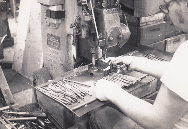 An Irwin employee works at a hole-punching machine, 1972